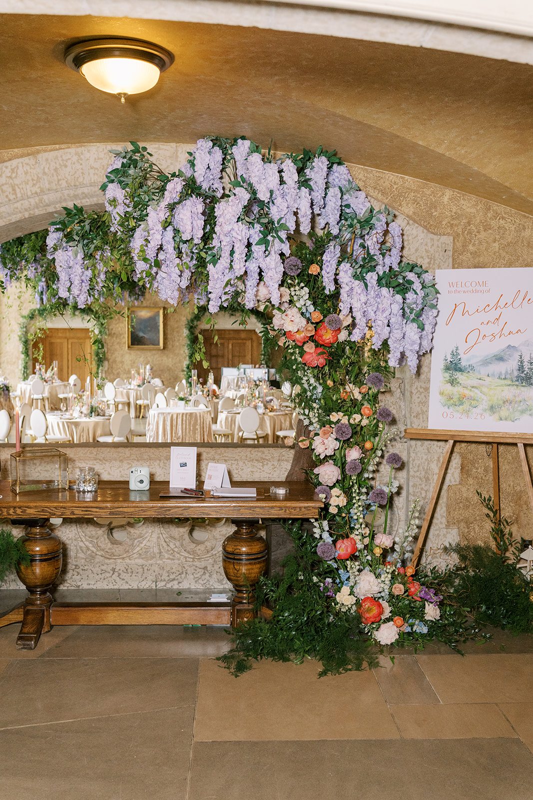 Lottie Colourful garden inspired floral arch with coral peonies, blush roses, blue delphinium, lavender flowers and trailing greenery.