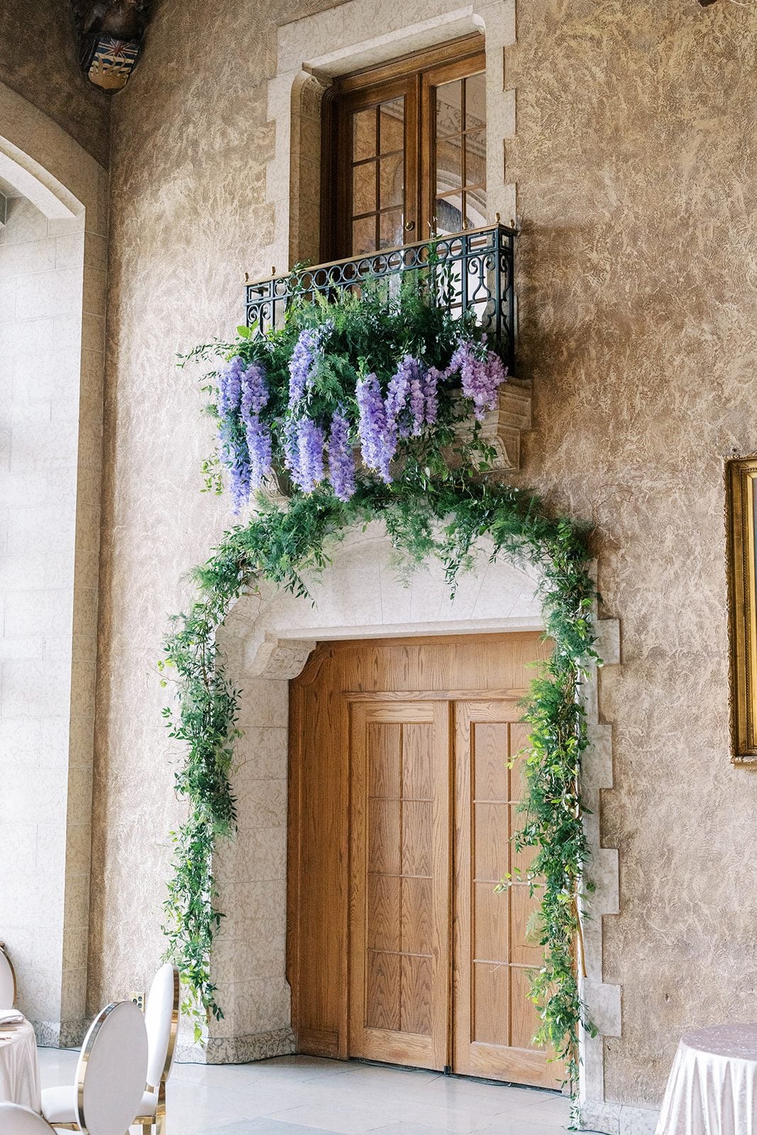 Lottie Lush greenery and cascading lavender wisteria decorating the stone arches of Mount Stephen Hall at the Fairmont Banff Springs.