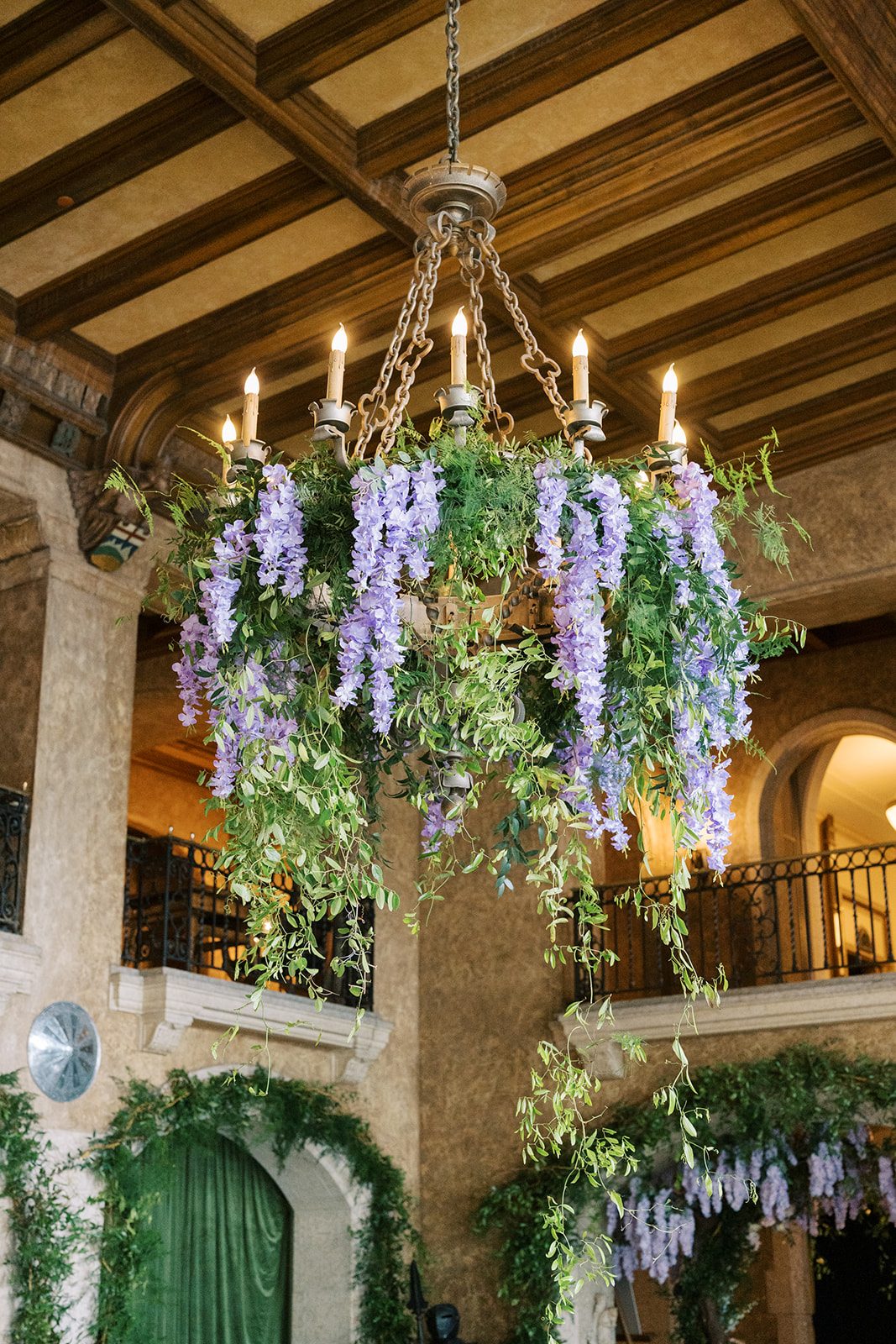 Lottie Fairmont Banff Springs chandelier covered in cascading greenery and lavender wisteria for a garden inspired wedding reception.