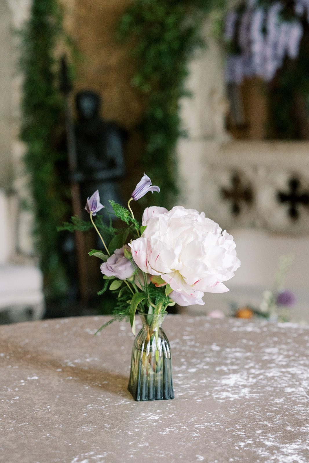 Lottie Blush peony and lavender flowers arranged in a small green glass bud vase.