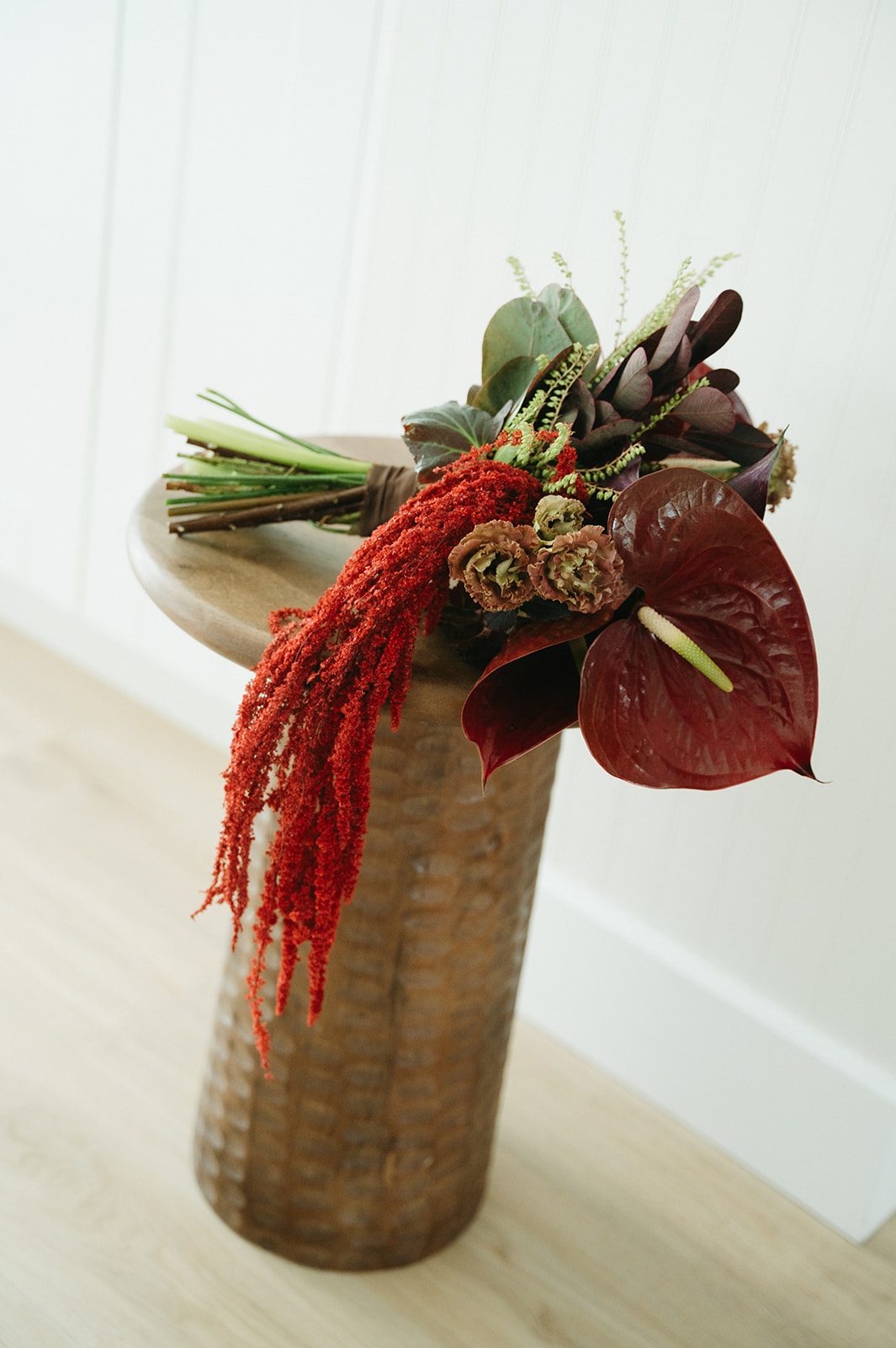 Andi + Logan Sculptural bridal bouquet featuring burgundy anthurium, dark foliage, calla lilies and red hanging amaranthus.