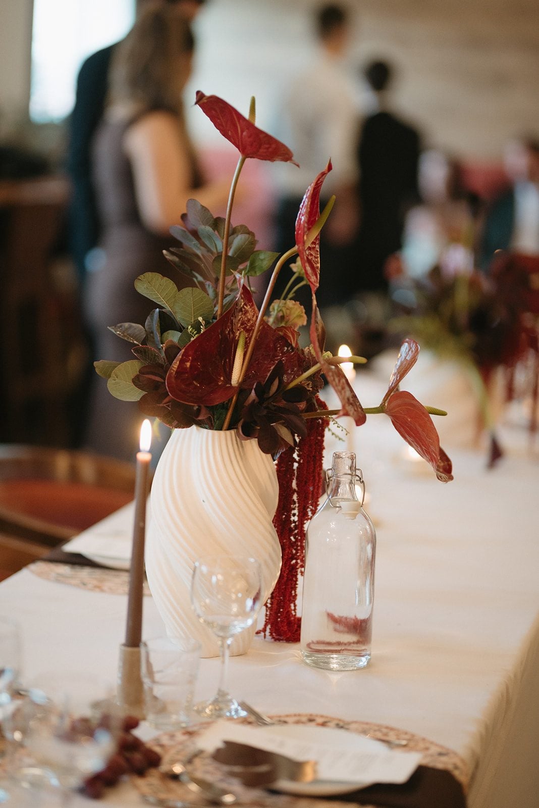 Andi + Logan Sculptural wedding flower arrangement with burgundy anthurium, textural blooms, rich foliage and cascading amaranths.