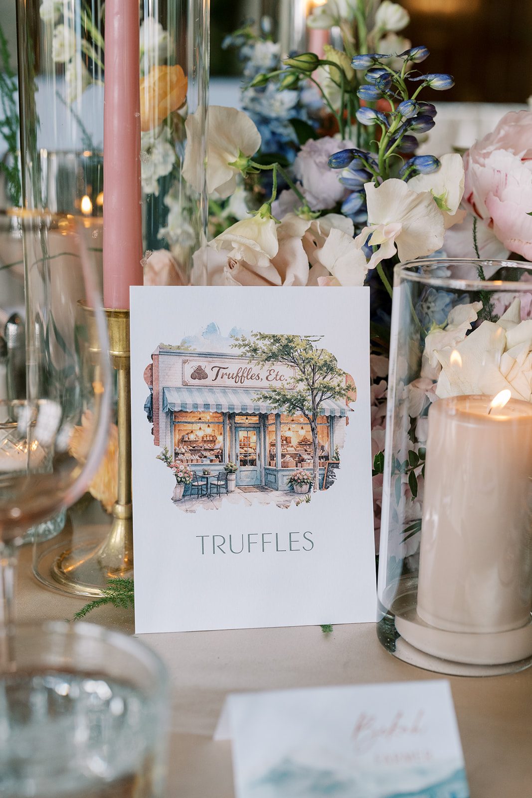 Lottie Illustrated Truffles table card nestled among colourful wedding flowers and candlelight.
